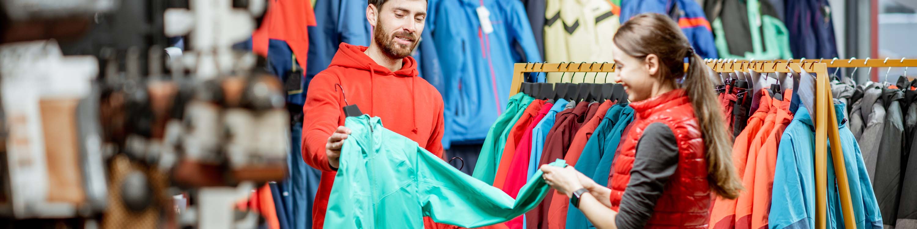 Image of sales associate showing a customer a winter ski jacket.